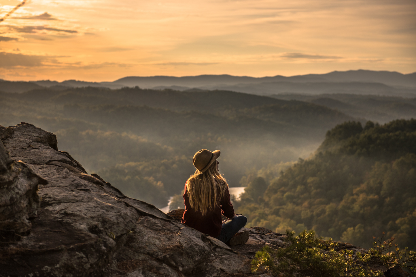 Woman Sitting on Mountain Top at Sunset